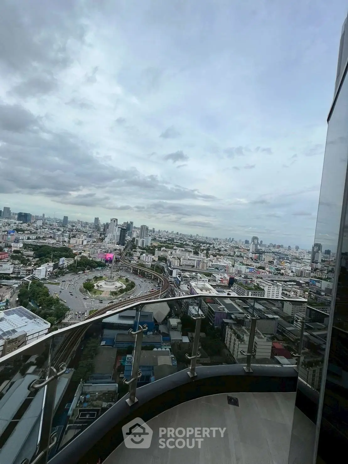 Stunning cityscape view from a high-rise balcony with sleek glass railing.