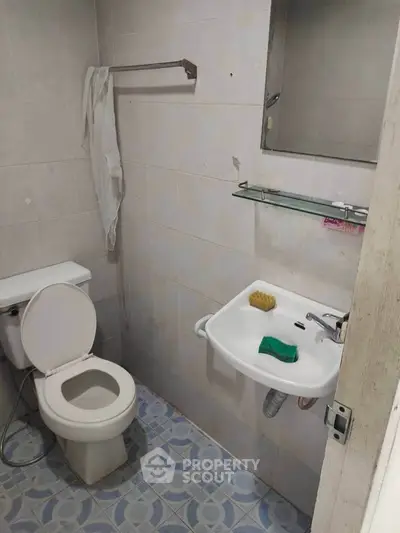 Compact bathroom with toilet, sink, and tiled floor, ideal for small spaces.