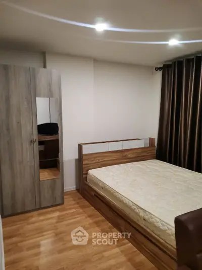 Cozy bedroom with wooden flooring and modern furniture, perfect for relaxation.