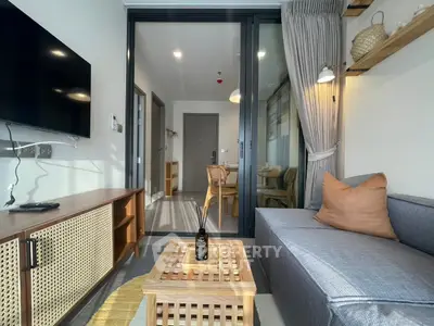 Modern living room with stylish furniture and natural light, featuring a cozy sofa and wall-mounted TV.