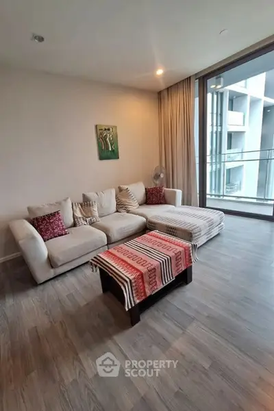 Spacious living room with modern decor and large windows overlooking balcony in luxury apartment.