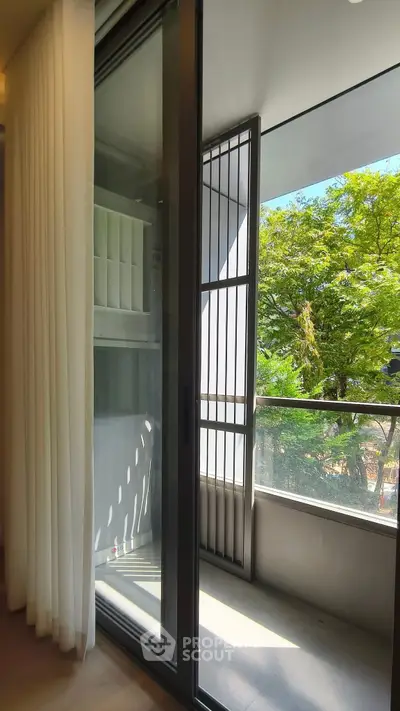 Modern apartment balcony with sliding glass doors and lush green view