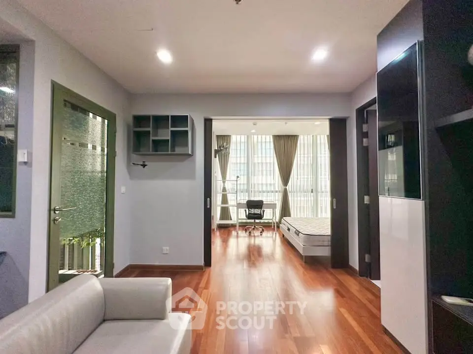 Spacious modern apartment with open layout and hardwood floors, featuring a cozy living area and a bright bedroom.