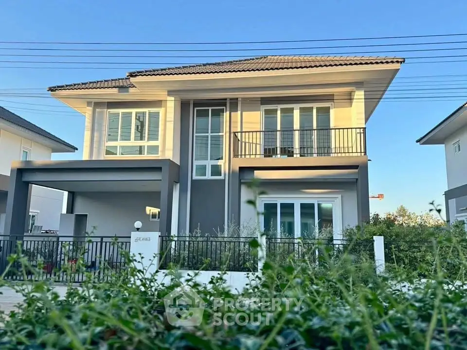 Modern two-story house with balcony and garden in a serene neighborhood.