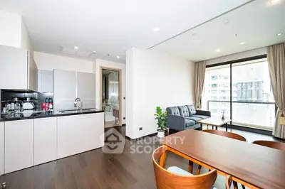Modern open-plan living room with kitchen in a high-rise apartment, featuring sleek furniture and large windows.