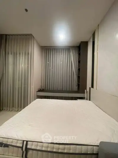 Spacious bedroom with modern decor and large windows for natural light.