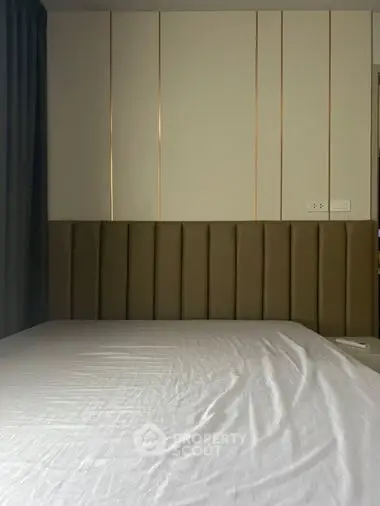 Elegant bedroom with a large comfortable bed set against a stylish paneled wall, creating a serene and sophisticated sleeping space.