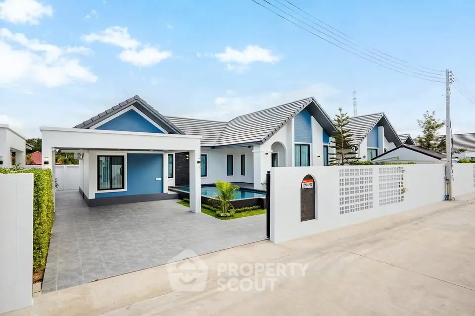 Modern blue and white house with spacious driveway and lush greenery