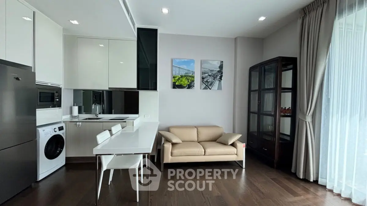 Modern living room with kitchen, featuring sleek appliances and elegant decor.