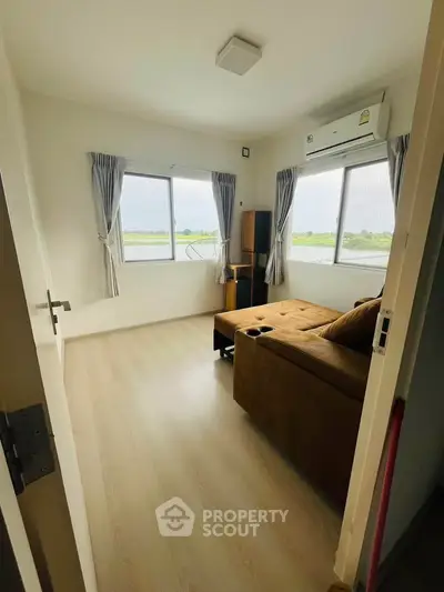 Cozy living room with large windows and a comfortable sofa, offering a serene view of the outdoors.