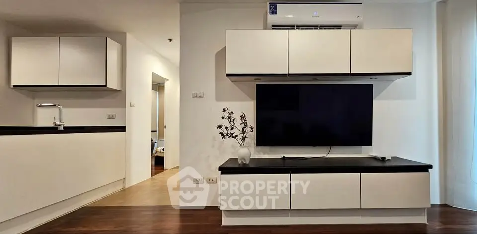 Modern living room with sleek cabinetry and wall-mounted TV, featuring minimalist design and warm lighting.