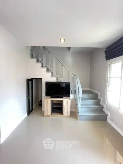 Modern living room with sleek staircase and natural light