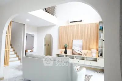 Modern living room with stylish decor and natural light, featuring a cozy white sofa and elegant wooden accents.