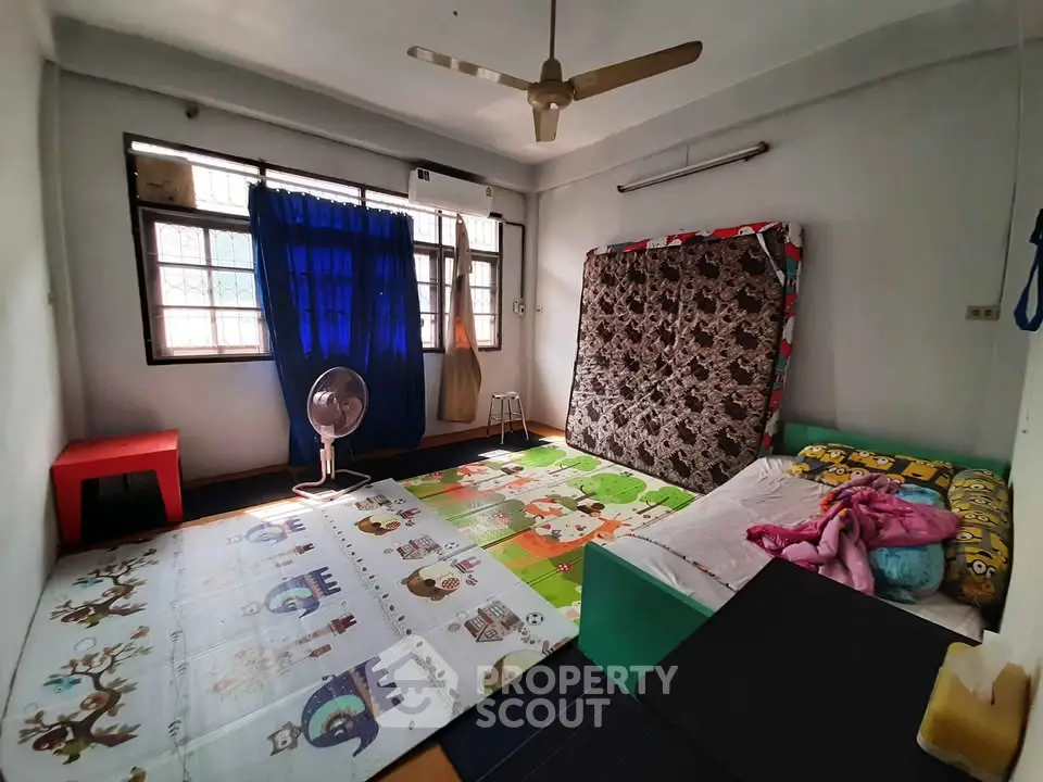 Cozy bedroom with colorful decor and ample natural light from large windows.