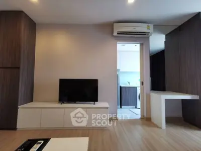 Modern living room with sleek design and open kitchen view, featuring wooden flooring and built-in air conditioning.