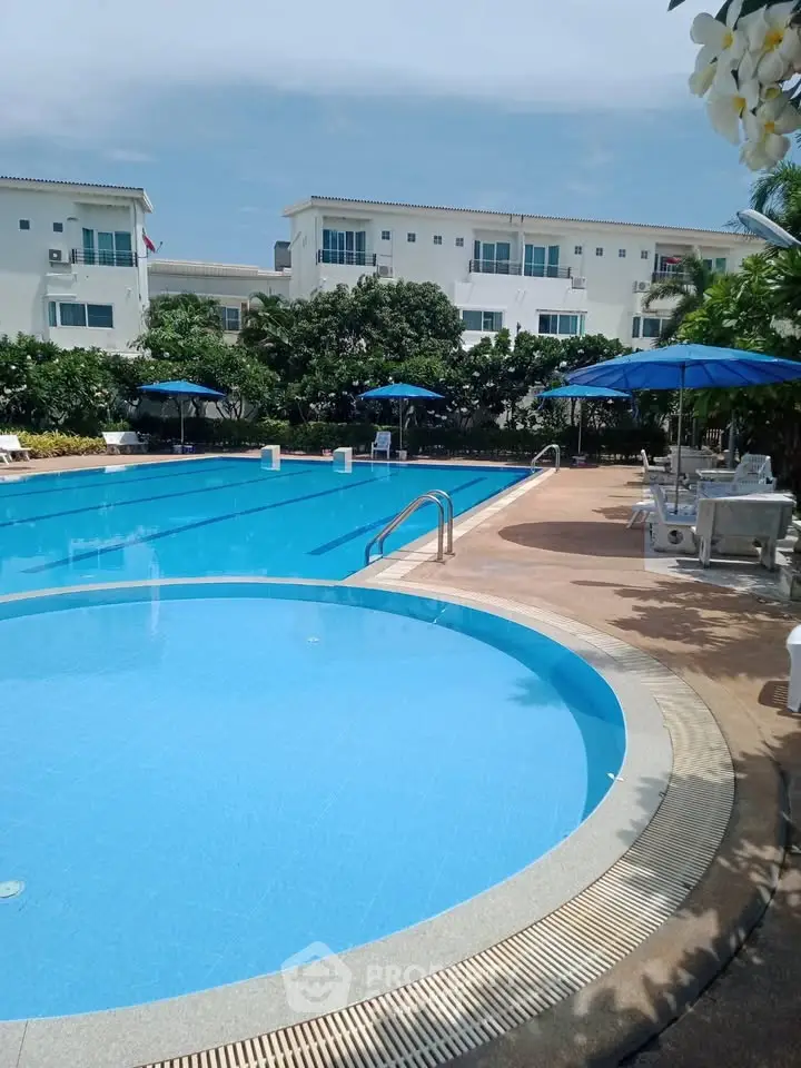 Luxurious residential complex with pristine swimming pool and sun loungers, perfect for relaxation.