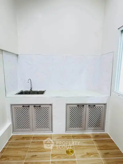 Modern kitchen with sleek cabinetry and tiled backsplash, featuring a stainless steel sink and ample counter space.