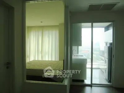 Modern apartment interior with bedroom and balcony view, featuring large windows and sleek design.