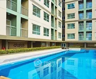 Modern apartment building with a pristine swimming pool and lush greenery.