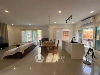 Spacious open-plan living room with modern kitchen and dining area, featuring large windows and natural light.