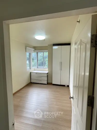 Spacious bedroom with large window and built-in wardrobe, perfect for natural light lovers.