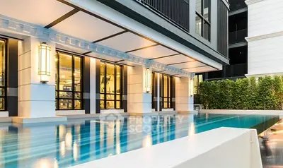 Luxurious modern building exterior with sleek pool and elegant lighting.