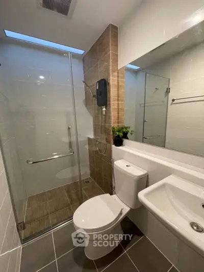 Modern bathroom with glass shower and sleek fixtures in contemporary apartment.