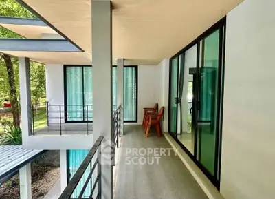 Modern balcony with glass doors and outdoor seating in a contemporary home