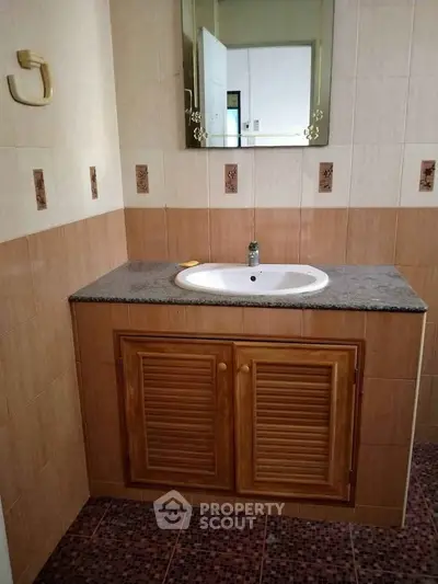 Charming bathroom with wooden vanity and tiled walls, perfect for a cozy home.