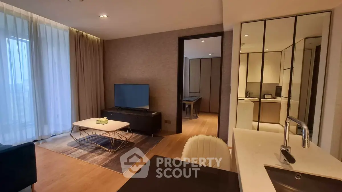 Modern living room with sleek design and open kitchen layout, featuring stylish furniture and ample natural light.