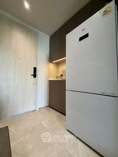 Modern kitchen with sleek fridge and minimalist design in a contemporary apartment.