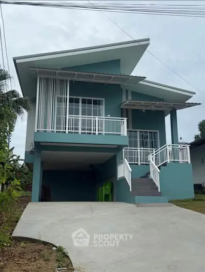 Modern teal house with unique roof design and spacious driveway, perfect for contemporary living.