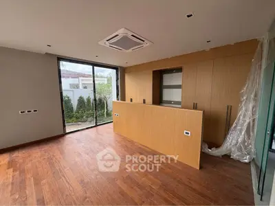 Modern kitchen with wooden flooring and large glass doors opening to a garden view.