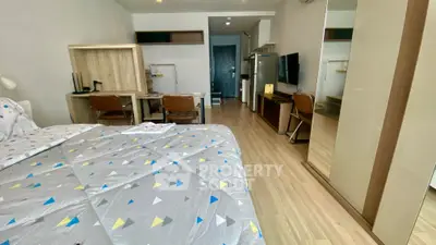 Modern studio apartment with cozy bedroom and study area, featuring sleek wooden flooring and contemporary furniture.