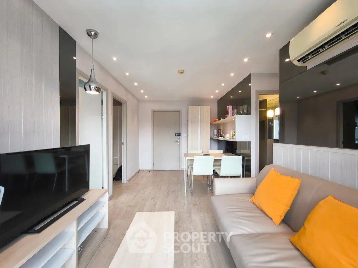 Modern living room with sleek design, featuring a comfortable sofa, dining area, and wall-mounted TV.