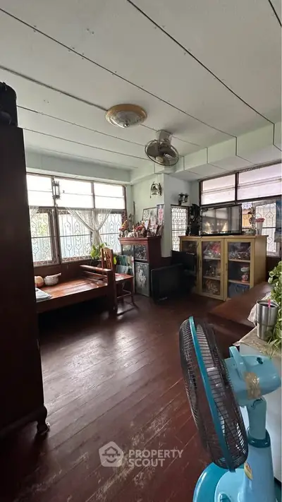 Charming vintage living room with wooden floors and large windows.