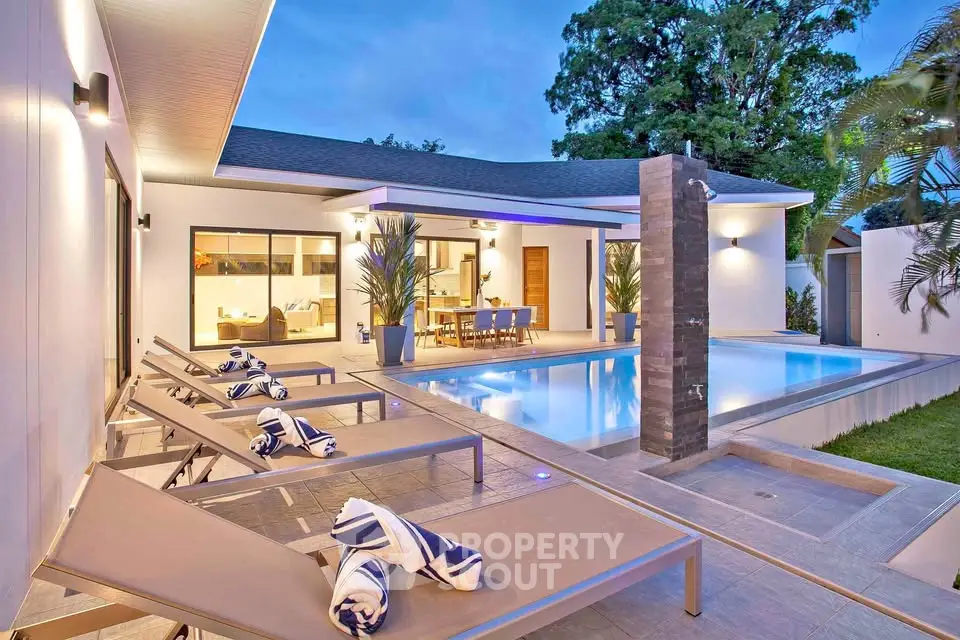 Luxurious modern home with poolside lounge area and elegant outdoor dining space.