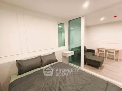 Modern bedroom with sleek design and adjacent living area in open layout apartment.