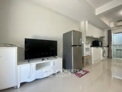 Modern open-layout kitchen with appliances and TV in a bright living space.