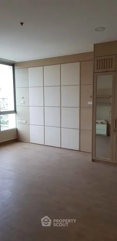Spacious modern bedroom with large window and built-in wardrobe in a stylish apartment.
