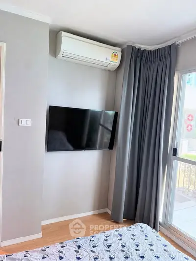 Modern bedroom with wall-mounted TV and air conditioning, featuring large window with curtains.