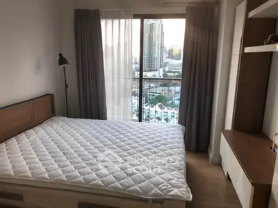 Cozy bedroom with city view, featuring a large window and modern furnishings.
