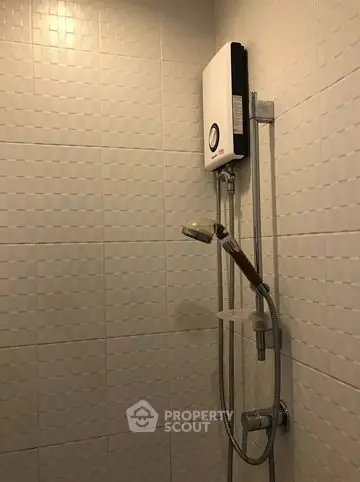 Modern bathroom with sleek shower and water heater in a tiled setting.