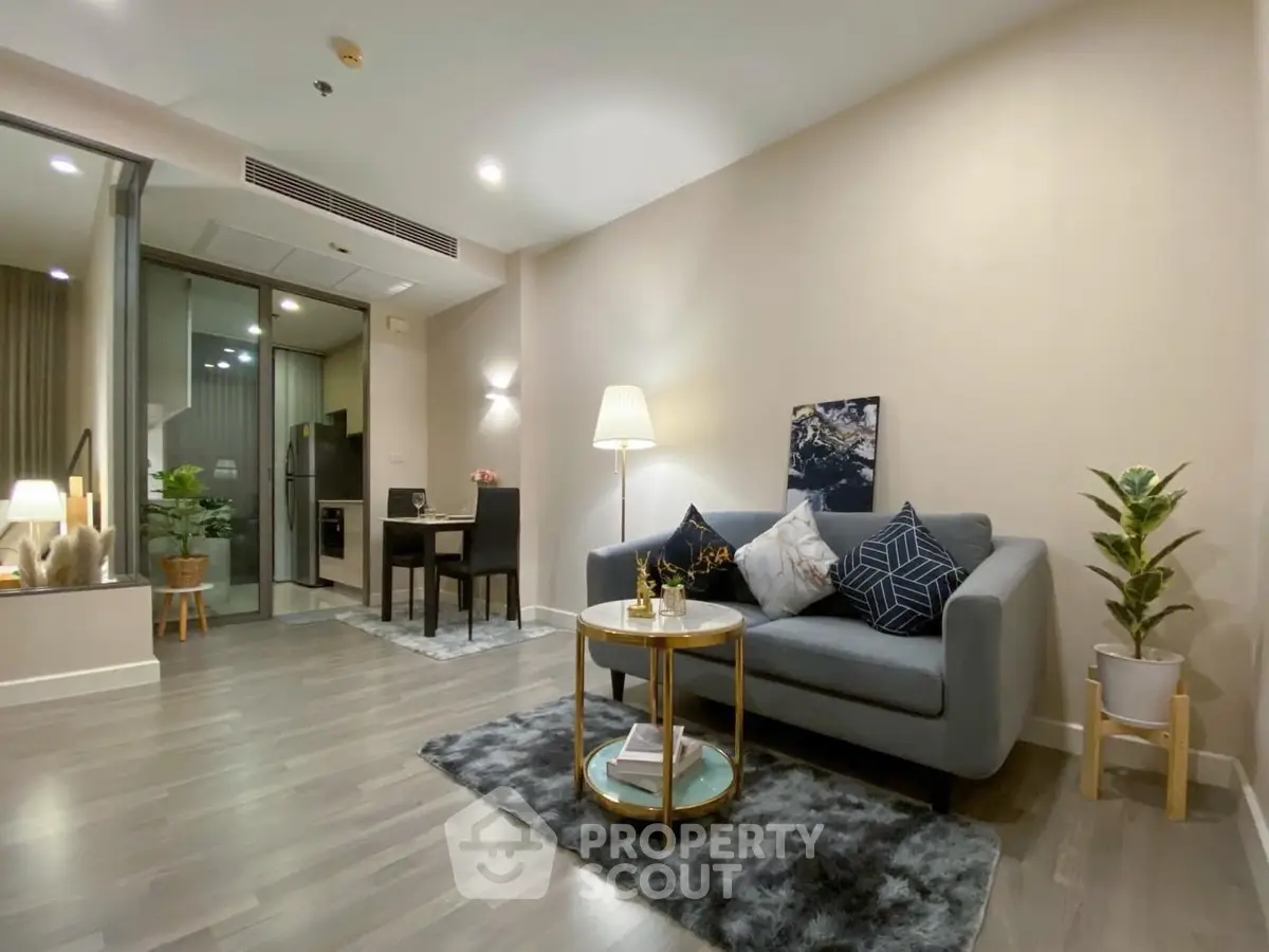 Elegant living room with modern furnishings, sleek grey flooring, and ambient lighting leading to a cozy balcony, perfect for urban living.