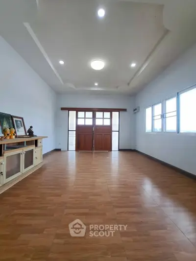Spacious living room with wooden flooring and large windows for natural light.