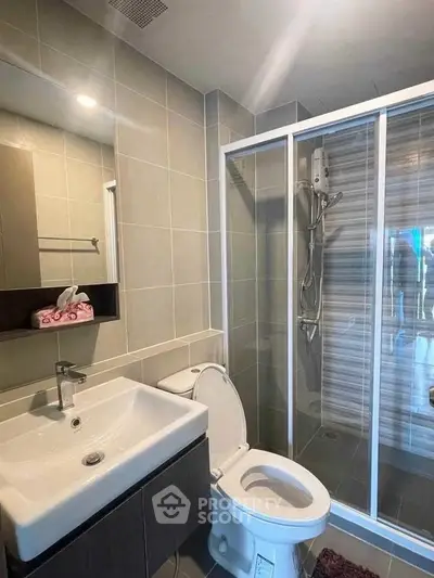 Modern bathroom with glass shower and sleek fixtures in contemporary home.