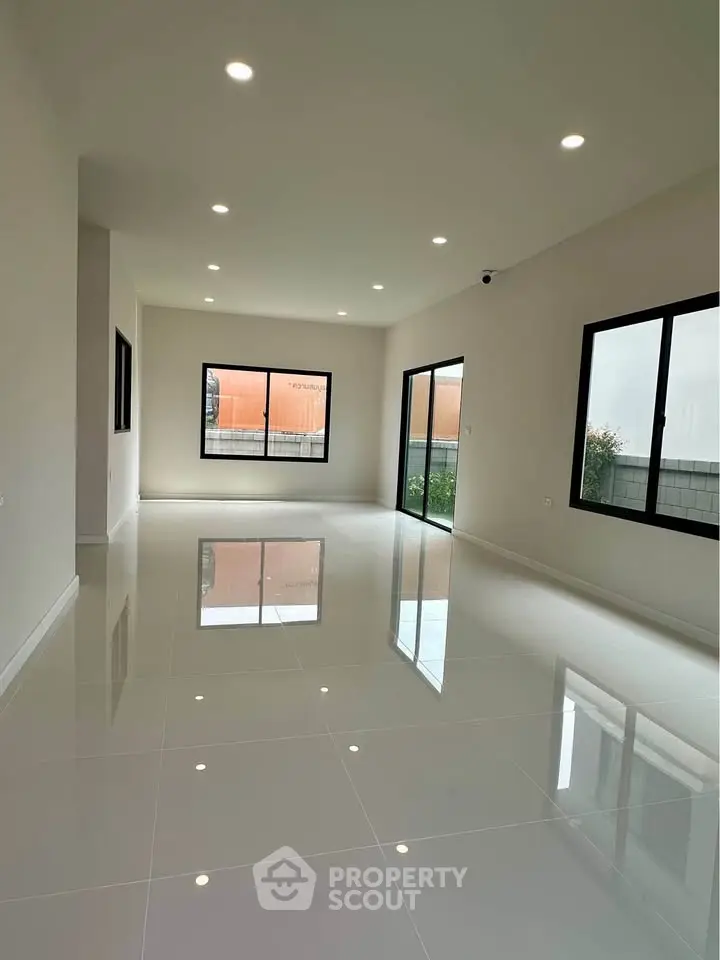 Spacious modern living room with large windows and glossy tiled floors