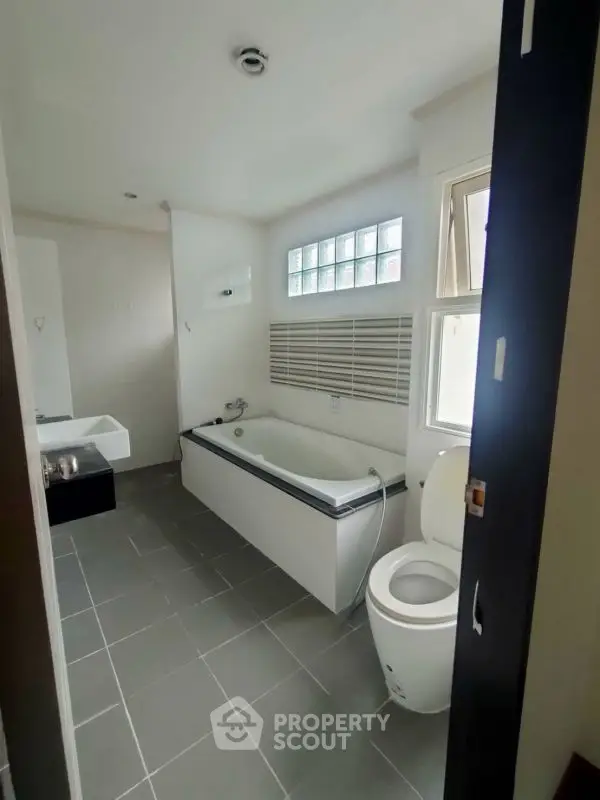 Modern bathroom with bathtub and sleek design, featuring large window for natural light.