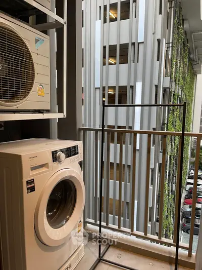 Urban balcony with washing machine and modern architectural view.
