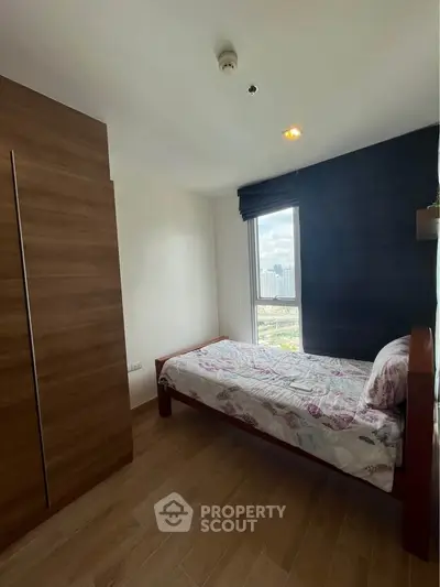 Cozy bedroom with single bed and city view, perfect for urban living.